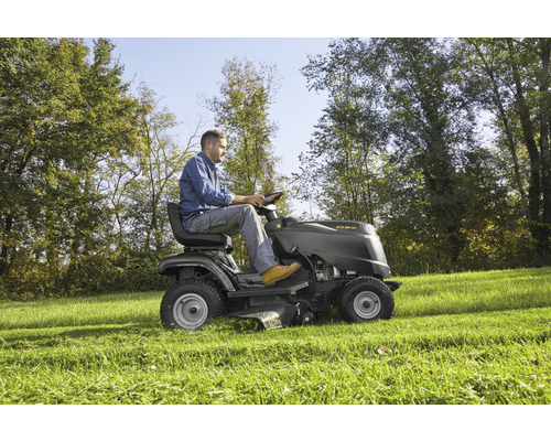Mann fährt Rasentraktor auf einer Wiese