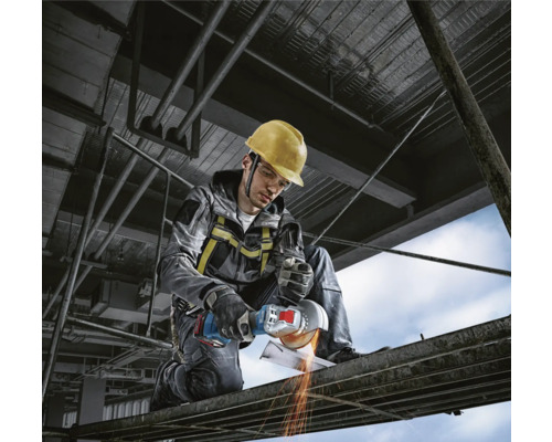 Handwerker mit Schutzhelm, Sicherheitsbrille und Winkelschleifer bei der Metallbearbeitung auf einer Baustelle.