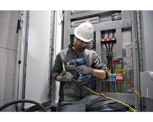 Elektriker mit Heißluftpistole bei der Arbeit an einer elektrischen Anlage