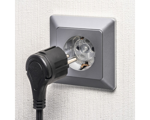 Steckdose mit eingestecktem Stecker an der Wand