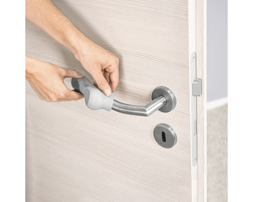 Person befestigt eine Griffverlängerung an einem Türgriff aus Edelstahl