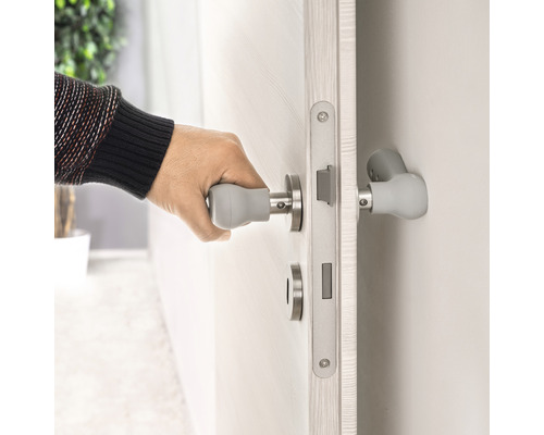 Eine Person öffnet eine Tür mit einem Türgriff mit Griffverlängerung.