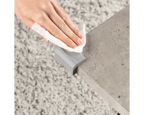 Eckenschutz an Tischkante befestigt, der mit einem Tuch gereinigt wird