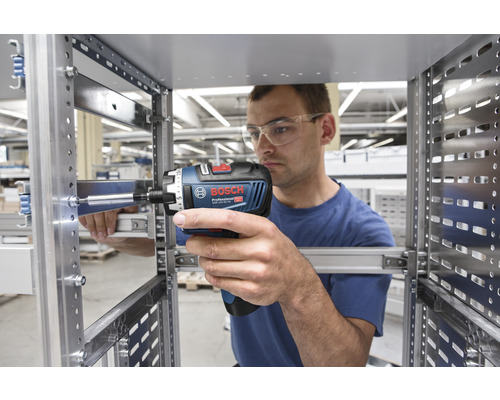Mann schraubt mit einem Akkuschrauber ein Metallregal zusammen