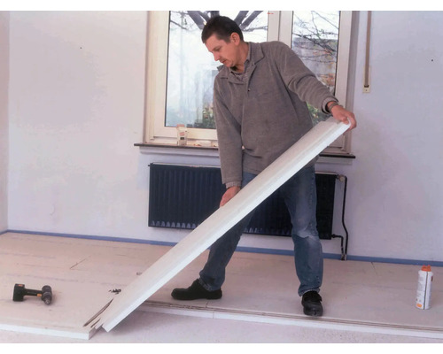 Ein Mann verlegt eine Fußleiste in einem Raum.