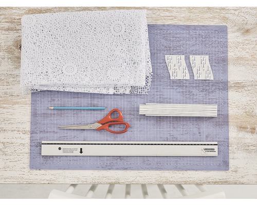 Bastelmaterialien, darunter Stoff, Schere, Bleistift, Lineal und Schneidematte