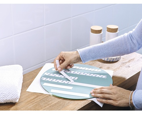 Aufkleben von Spiegelklebeband auf einen runden Spiegel im Badezimmer