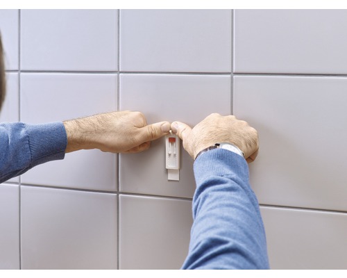 Mann befestigt einen Feuchtigkeitssensor an der Wand