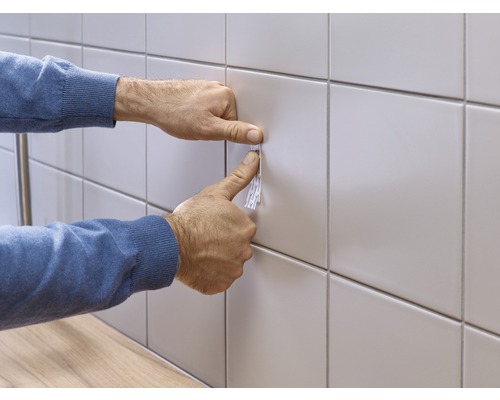 Anbringen eines Klebestreifens an einer gefliesten Wand