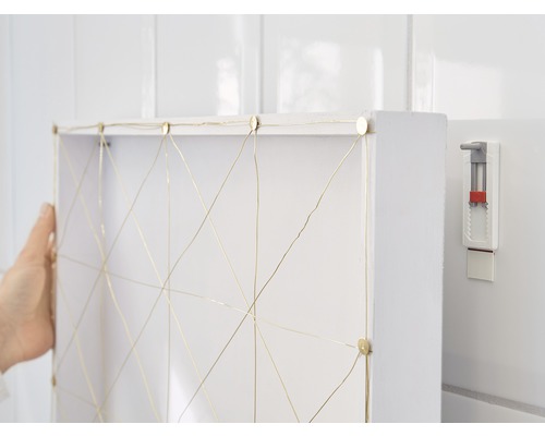 Weißes Wandregal mit goldfarbener Drahtdekoration