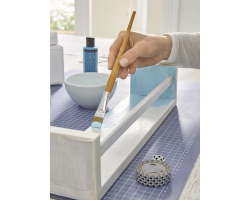 Bemalen eines Holzregals mit einem Pinsel und Farbe