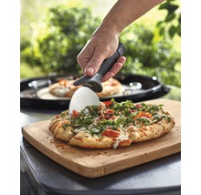 Eine Pizza wird mit einem Pizzaschneider auf einem Schneidebrett geschnitten.
