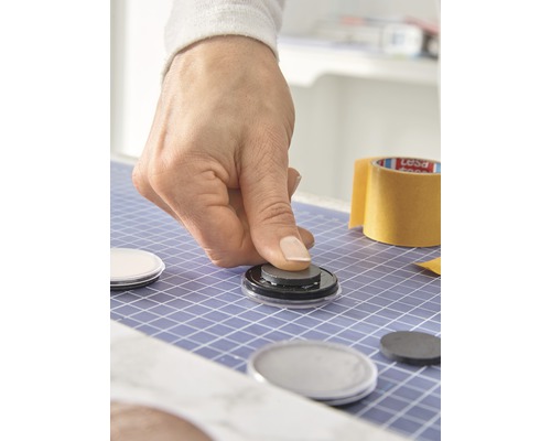 Person befestigt Magneten auf runder Oberfläche