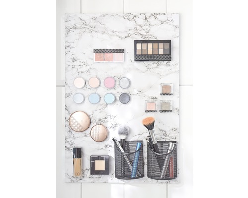 Kosmetikprodukte an einer Marmorplatte befestigt, inklusive Lidschattenpaletten, Make-up-Pinsel und flüssiger Foundation