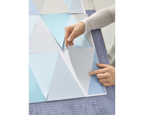Person ordnet dreieckige Tapetenmuster an