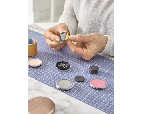 Frau befestigt Magnet an Kosmetikdose auf einer Schneidematte
