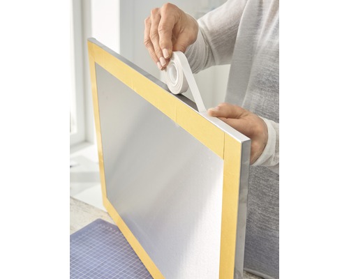 Doppelseitiges Klebeband wird auf einen silberfarbenen Rahmen aufgebracht