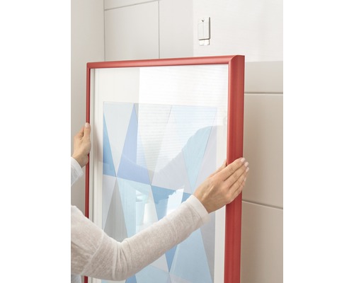 Person hängt gerahmtes Bild an Wand auf