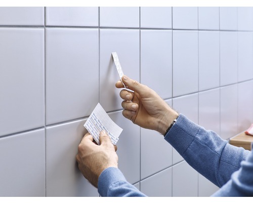 Anwender bringt Klebestreifen auf Fliesen an