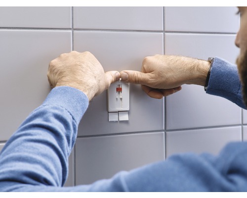 Mann montiert ein Befestigungssystem an einer gefliesten Wand