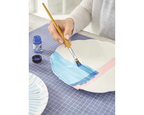 Dekoration eines Tellers mit Pinsel und Farbe