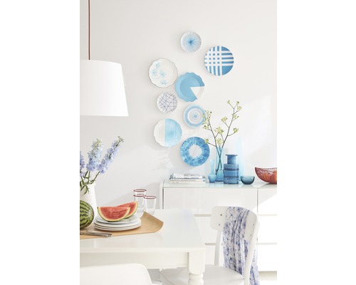 Helle Esszene mit Dekorationsgeschirr an der Wand, Obst und Geschirr auf dem Tisch und dekorativen Vasen auf der Kommode.