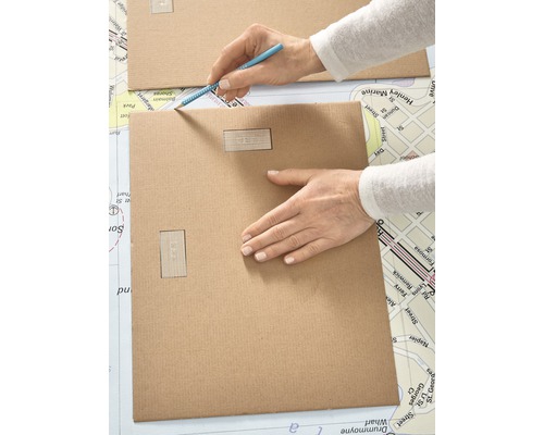 Person zeichnet mit einem Stift auf ein Stück Karton.