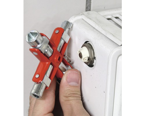 Ein Mann benutzt einen Heizkörperschlüssel an einem Heizkörper.