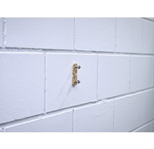 Zwei goldfarbene Halterungen sind an einer weißen Wand befestigt.
