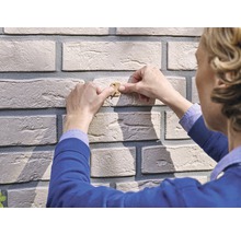 Person befestigt Riemchen an einer Wand