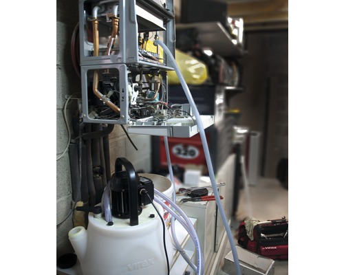 Geöffneter Heizkessel wird mit Spülpumpe gereinigt.