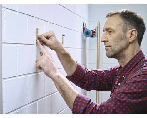 Mann befestigt einen Holzhaken an einer Wand