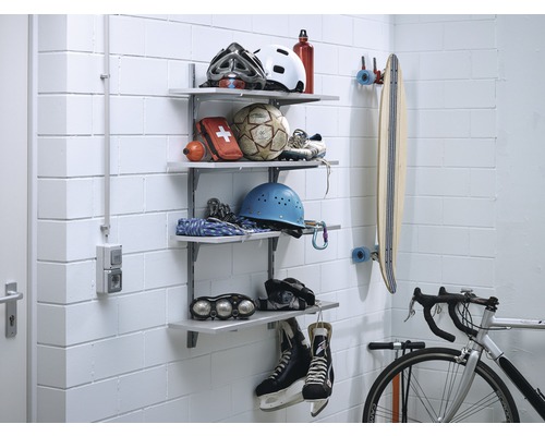Regalsystem mit Sportausrüstung an einer Wand, inklusive Helmen, Ball, Erste-Hilfe-Set, Skateboard, Fahrrad und Eishockey-Schlittschuhen