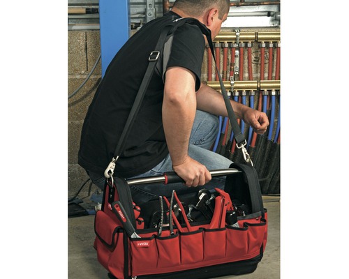 Handwerker mit einer roten Werkzeugtasche gefüllt mit Werkzeugen, getragen über der Schulter