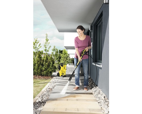 Frau reinigt Gehwegplatten mit einem Hochdruckreiniger von Kärcher