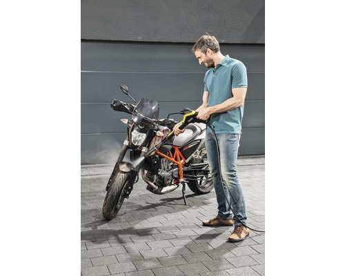 Mann reinigt Motorrad mit Hochdruckreiniger