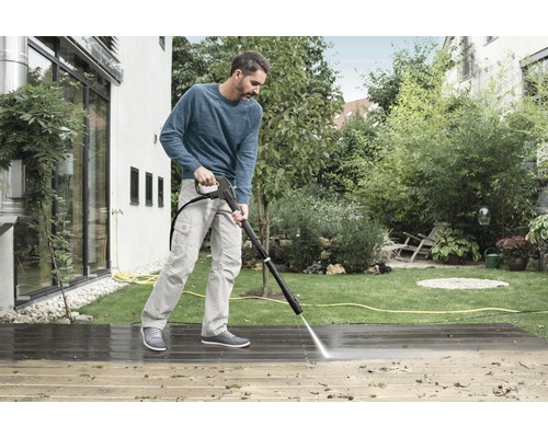 Mann reinigt Holzterrasse mit Hochdruckreiniger