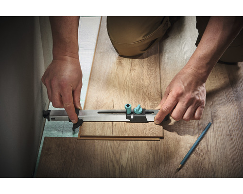 Person benutzt ein Messwerkzeug, um ein Laminatstück zu messen