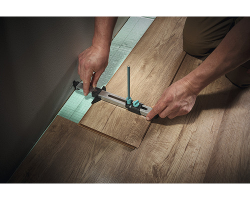 Zimmerer, der mit einem Anreißwerkzeug einen Laminatboden verlegt