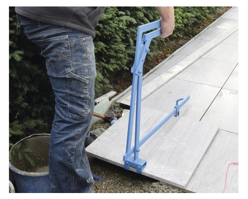 Person verlegt Gehwegplatten mit einem Plattenheber.
