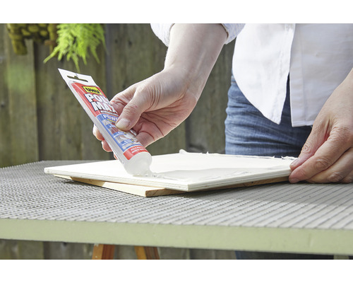 Eine Person trägt UHU Alleskleber auf eine Holzoberfläche auf