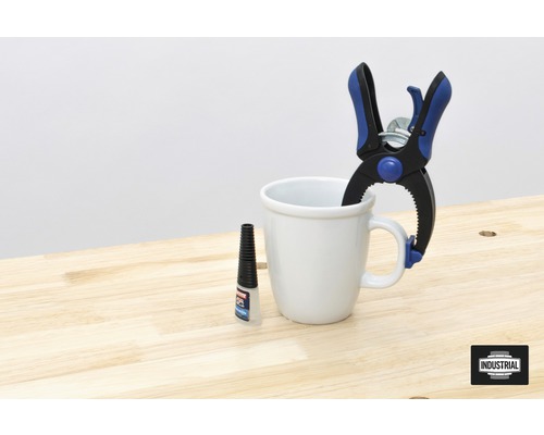 Leimflasche, Schraubzwinge und Tasse auf einer Werkbank