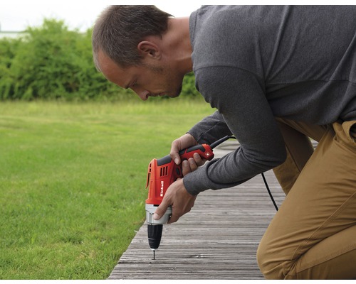Mann bohrt mit einer Bohrmaschine ein Brett fest