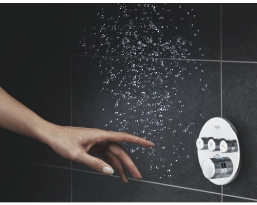 Brause mit Bedienelement und Hand unter Wasserstrahl vor dunklem Hintergrund