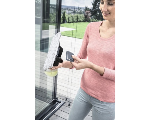 Eine Frau reinigt eine Glasscheibe mit einem Fensterreiniger.