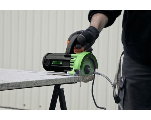 Eine Hand bedient eine Fliesenschneidmaschine von Eibenstock, um eine Fliese zu schneiden.