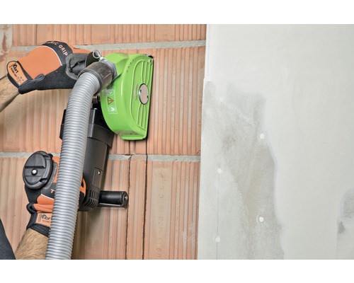 Eine Mauernutfräse im Einsatz an einer Ziegelwand mit angrenzender Gipskartonplatte