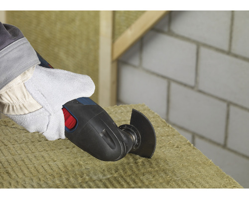 Eine Person schneidet mit einem Multifunktionswerkzeug Dämmmaterial.