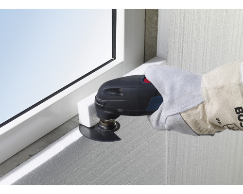 Oszillierendes Elektrowerkzeug im Einsatz zum Zuschneiden von Dämmstoffplatten an einem Fensterrahmen