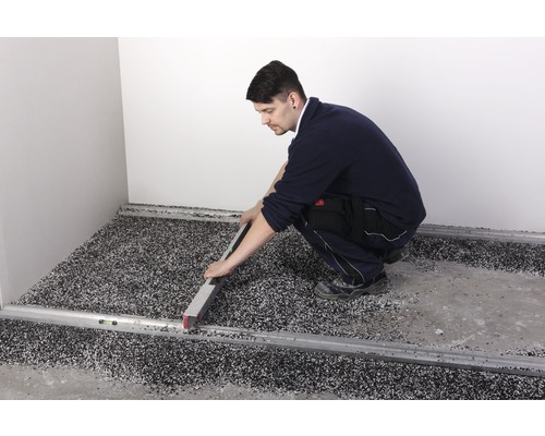 Ein Arbeiter nivelliert mit einer Wasserwaage einen Boden mit Epoxidharz.